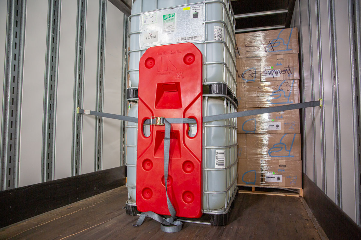 Freight Brace installed with straps against stacked liquid bins